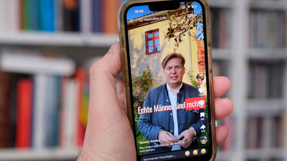 Hand hält ein Mobiltelefon auf dessen Display AFD Politiker Krah auf TikTok zu sehen ist