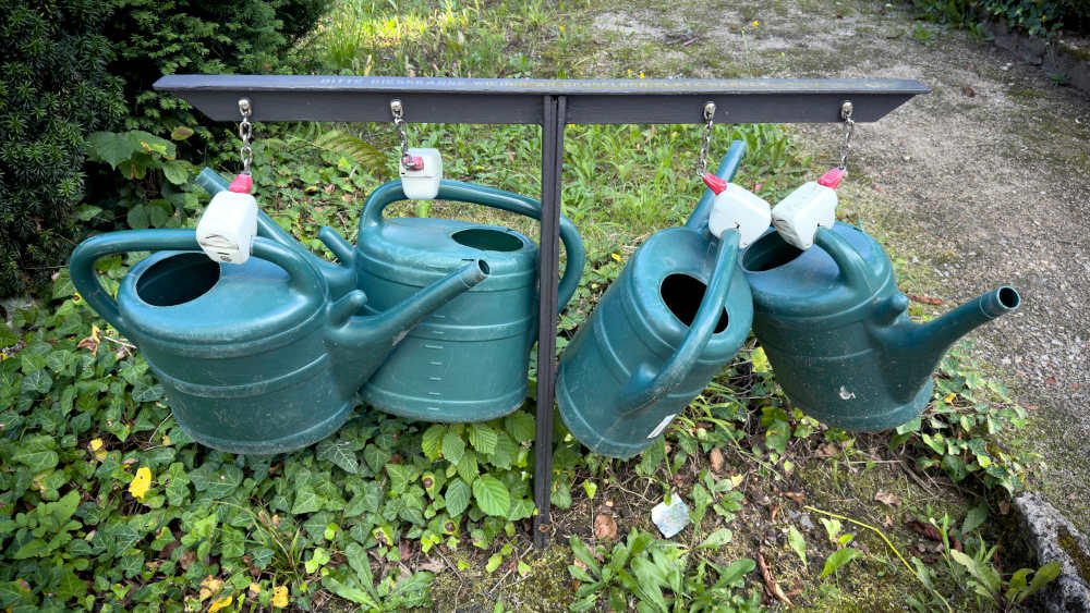 Abgeschlossene grüne Gießkannen gesichert gegen Diebstahl auf dem historischen Friedhof