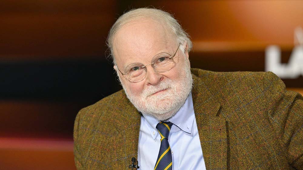 Mann mit Halbglatze und grünem Jackett.