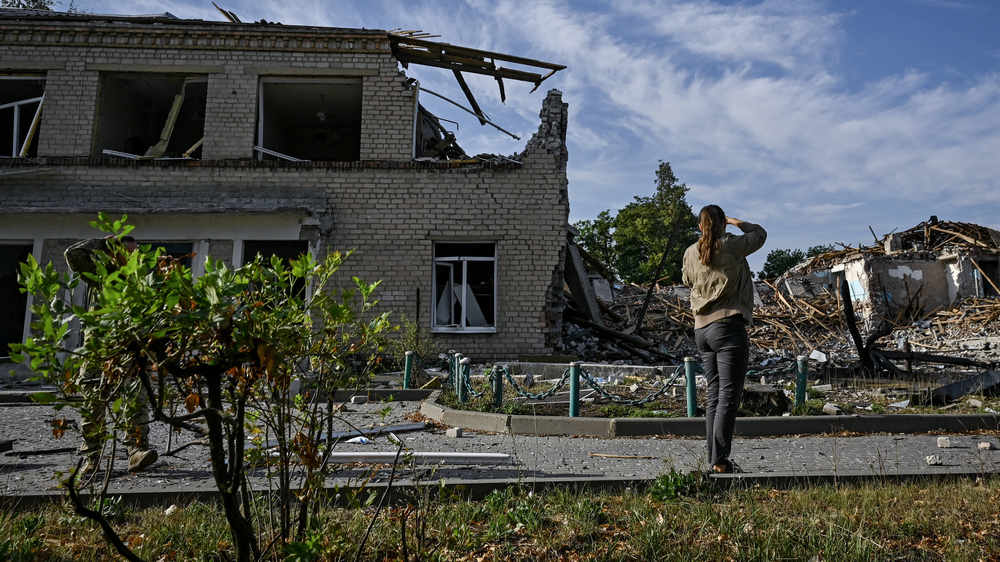 Frau steht vor zerstörtem Haus