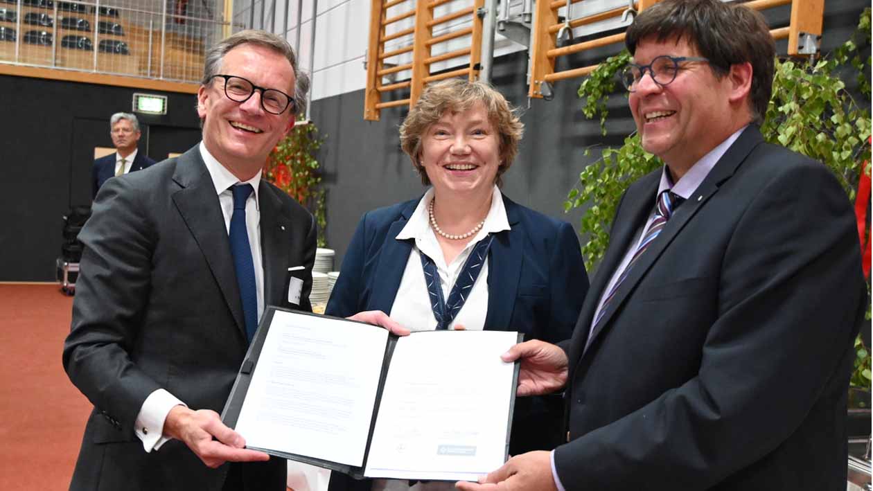 Zwei Männer und eine Frau halten einen Vertrag in die Kamera