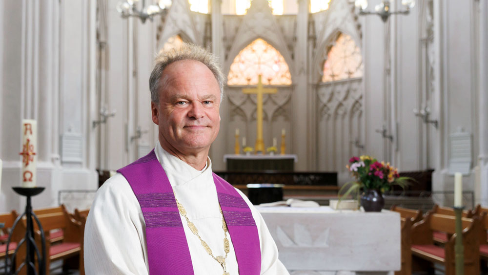 Bischof Tilman Jeremias steht in weißem Talar im Greifswalder Dom