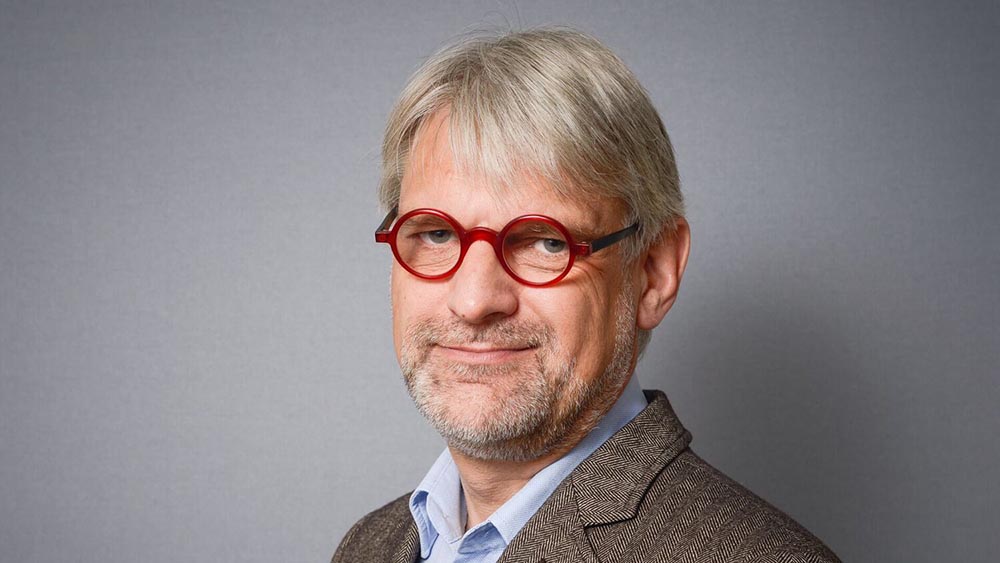 Älterer Mann mit grauem Haar und roter Brille.