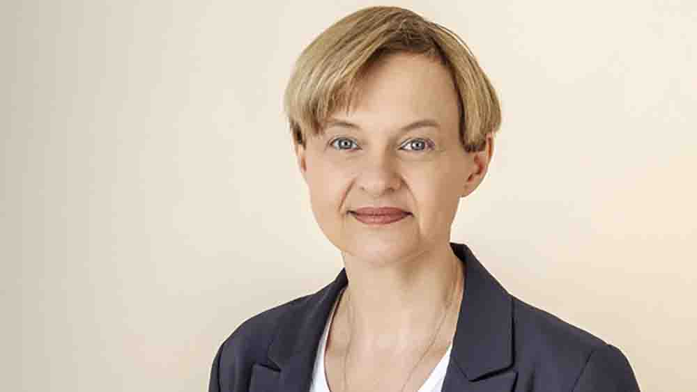 Frau mit blonder Kurzhaarfrisur vor einem hellen Hintergrund.