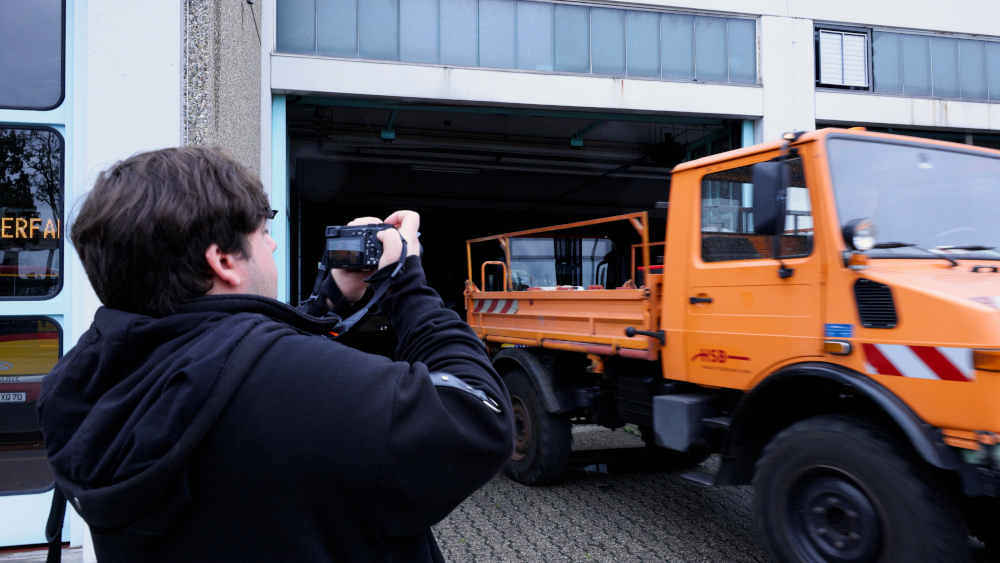 Mann filmt ein Fahrzeug vor einer Halle