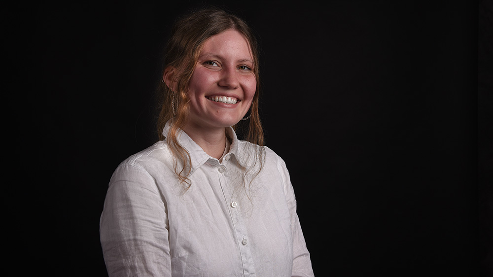 Frau mit weißer Bluse vor schwarzem Hintergrund