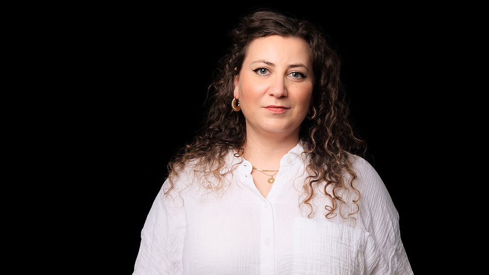 Frau in weißer Bluse vor schwarzem Hintergrund