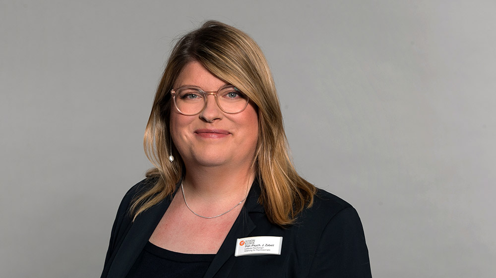 Blonde Frau mit Brille und schwarzer Bluse im Porträt