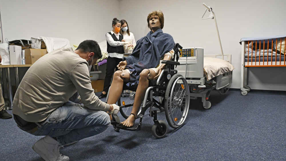 Pflegeausbildung an einer Puppe im Rollstuhl