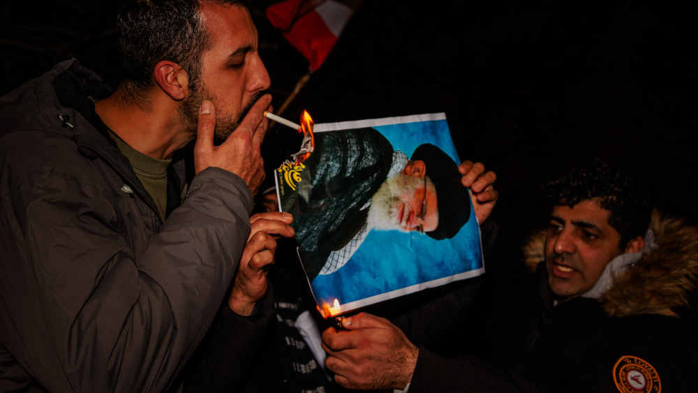 Mann zündet sich Zigarette an brennenden Mullah-Foto an