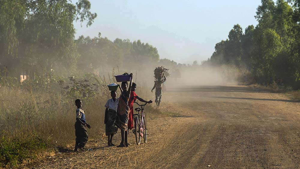Auf einer staubigen Straße laufen Menschen