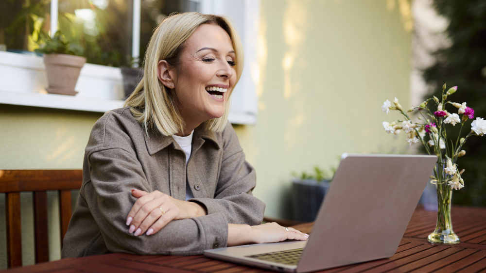 Frau sitzt lachend vor dem Laptop
