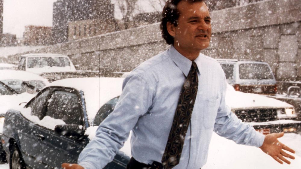 Mann im weißen Hemd mit Schlipps läuft durch eine Straße im Schnee