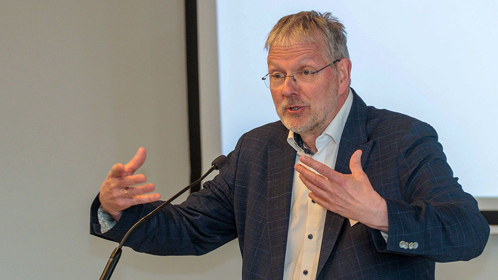 Mann mit Brille und grauen Haaren an Rednerpult