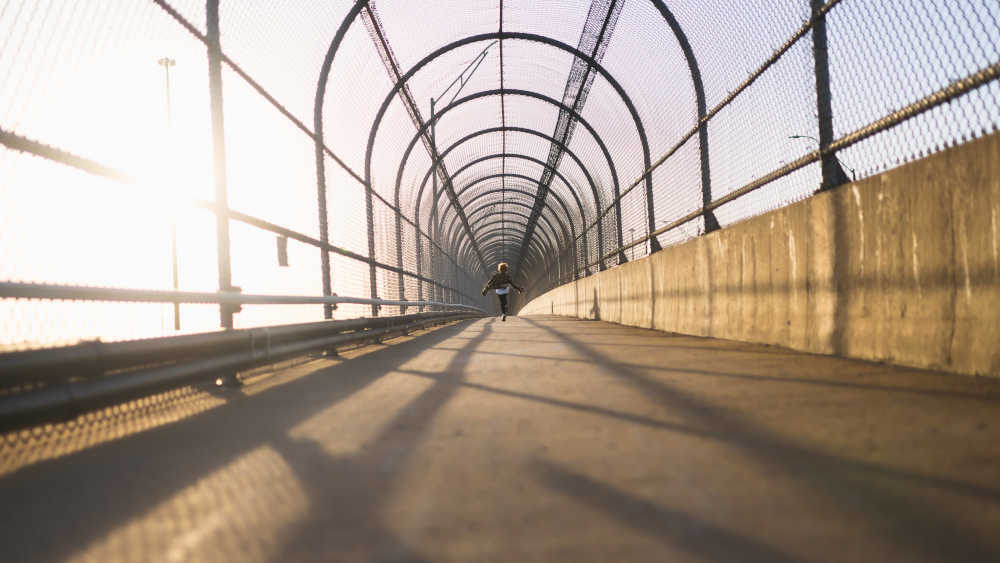 Junge läuft auf einer beleuchteten Fußgängerbrücke